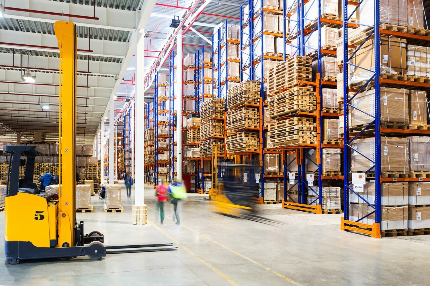 People walking in industrial warehouse next to forklift