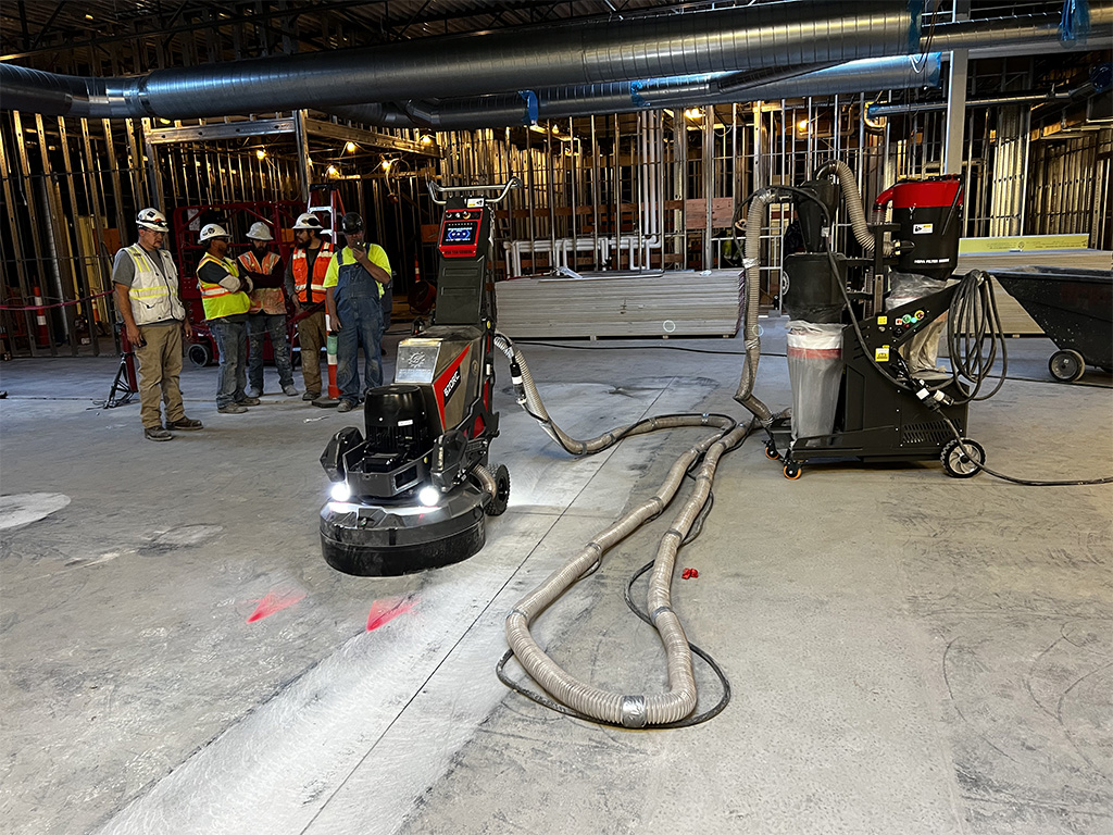 Crew running a remote controlled concrete floor grinder